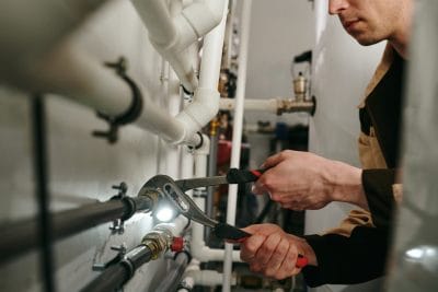 Technician inspecting commercial plumbing pipes in Lawndale